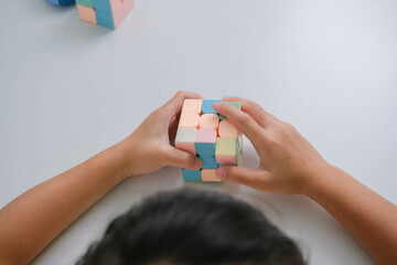 Asian little cute girl holding Rubik's cube in her hands and playing with it. Rubik's cube is a game that increases intelligence for children.