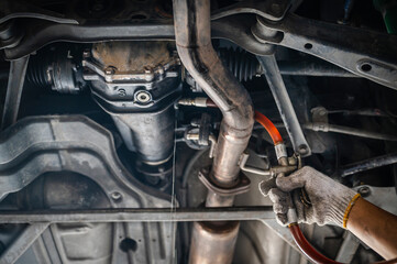 Auto mechanic filling rear differential fluid ,rear differential fluid service. - obrazy, fototapety, plakaty