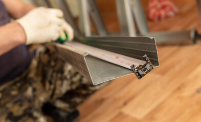 A man installs a metal profile for a wall in a room.