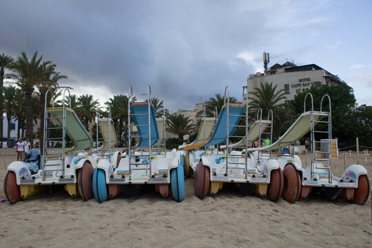 evocative image of pedal boats on the beach waiting to be used in the sea 
