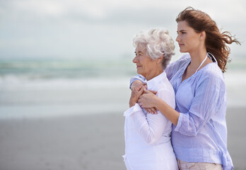 Beach, young woman and her senior mother embrace or look at horizon outdoors. Mock up, free and...