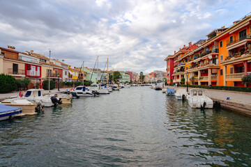Walk through the streets and canals of the port of Saplaya on a sunny day. Moored yachts and boats at the bright facades of houses. Spain