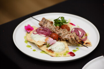 souvlaki with pita and tzatziki sauce on a white plate