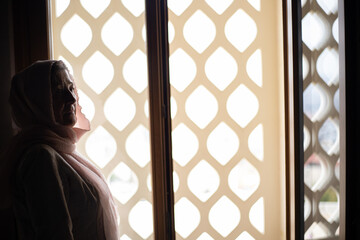 Woman in a scarf on her head near the window in the mosque