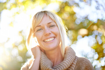 Women, face and smile portrait outdoor in nature with trees, happiness and lens flare in spring....