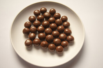 chocolate balls on a white plate on a white background