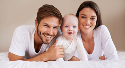 Happy portrait, dad and mom of baby kid on bed for love, care and quality time together to relax at...