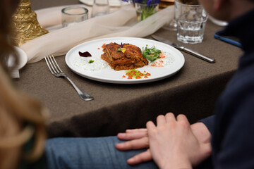 portion of traditional greek moussaka in white plate on a table in a restaurant