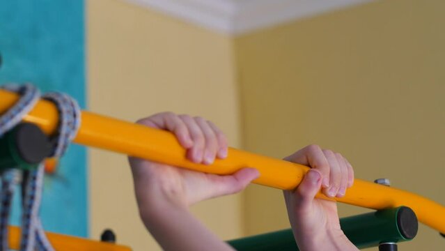 caucasian boy pulls up on the horizontal bar indoors, playing sports, child training, pulling up, schoolboy physical activity, exercise physical