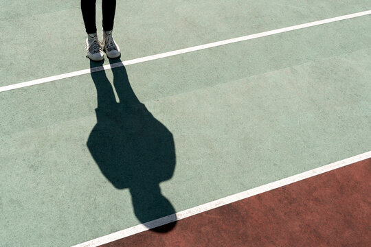 Girl standing on bright sun casting a long shadow