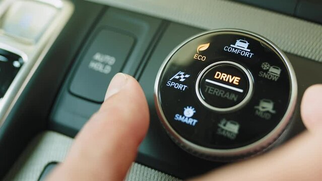 Manual selection of driving modes sport, eco, comfort button on a modern SUV. Electric car driver pressing eco button, environmental protection