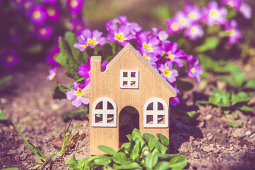 The symbol of the house stands among the purple flowers
