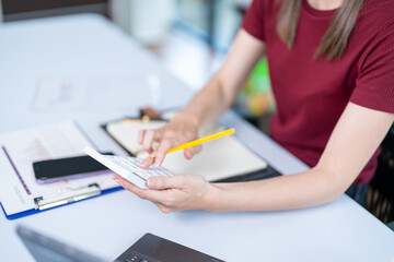 Closing of businessman or accountant hand holding pencil working on calculator to calculate business data accounting documents and a laptop computer at the office business idea
