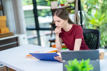 Very stressed business woman and female employee sitting in front of her computer with her hands in front of her eyes, feeling sad and depressed. Too much work - huge pile of paperwork at office table