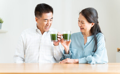 リビングで青汁を持つシニア夫婦