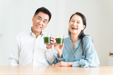 リビングで青汁を持つシニア夫婦