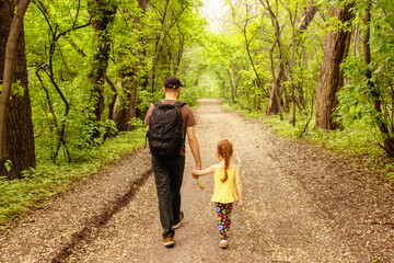 Fototapeta premium dad and daughter walk by the hand. dad give his daughter flowers