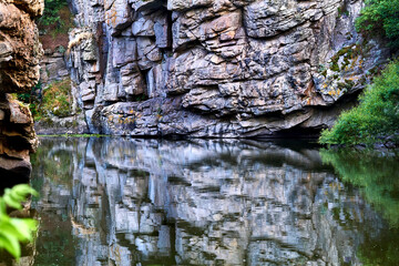 Summer deep rocky silver canyon with smoothly flowing water and reflection