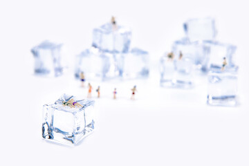 Miniature people in swimsuit resting on ice cube. Summer holiday. anti hot temp concept. isolate...