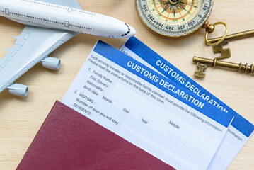 Customs declaration form on a wood table with a white model airplane. The purpose of the form is to...