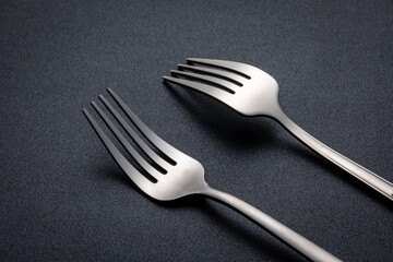 Stainless steel cutlery placed on a dark tabletop (cutlery), indoor photography light