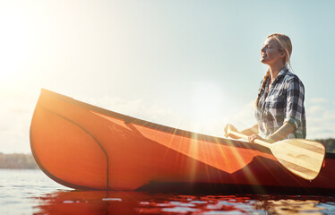 The best way to get around. an attractive young woman spending a day kayaking on the lake.