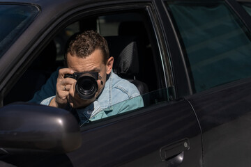 Paparazzi men or guy in sunglasse sits in her car and takes pictures of famous person.Spy with...
