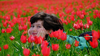 Naklejka premium Boy stretching in a field of tulips.