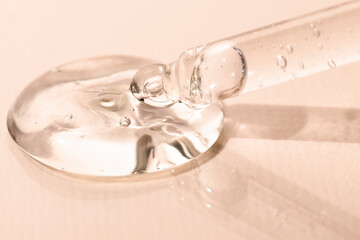 Dropper with hyaluronic acid on a beige background, front view. Aloe vera gel, liquid peptide with pipette, macro.