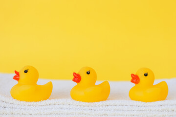 Stacked white towels and bath ducks on yellow background