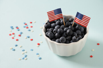 Blueberry decorated two US flags in white bowl on blue background. Concept preparations for Patriotic Independence Day 4th of july. Close up. Copy space.