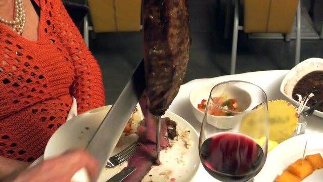 Brazilian picanha BBQ traditional method involves skewering meat on iron sword and roasting it over open flame. cooked to perfection, meat is expertly served on plate at Brazilian steakhouses