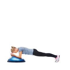 She enjoys her workouts. An attractive young woman using a bosu-ball for an upper body workout.