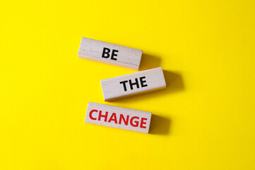 Naklejka premium Be the change symbol. Concept word Be the change on wooden blocks. Beautiful yellow background. Business and Be the change concept. Copy space