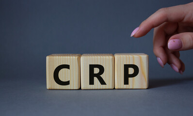 CRP - C-Reactive Protein Test symbol. Wooden cubes with word CRP. Doctor hand. Beautiful grey background. Medical and C-Reactive Protein Test concept. Copy space.