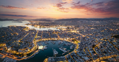 Aerial panorama of the illuminated Piraeus district in Athens, Greece, with Zea Marina and the ferry boat harbour in the background during evening time - obrazy, fototapety, plakaty