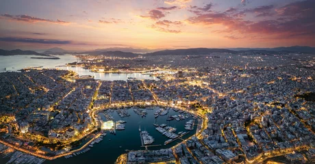Poster Aerial panorama of the illuminated Piraeus district in Athens, Greece, with Zea Marina and the ferry boat harbour in the background during evening time © moofushi
