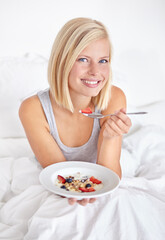 Obraz na płótnie Canvas Enjoying a healthy snack in the morning. A gorgeous blond eating fruit salad in bed.
