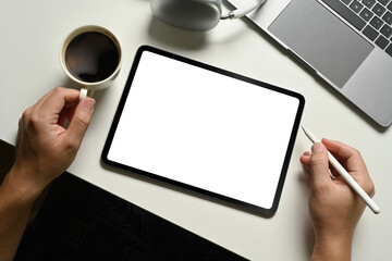 Above view of hand holding stylus pen, working with digital tablet one white office desk