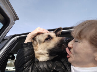 An adult girl and a dog in a car. The journey of a woman and an animal. Friendship of a shepherd pet and a mature lady