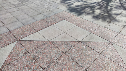 Fototapeta premium Gray tiles on the sidewalk in the city outdoors. Background and texture with lines and squares of tiles. Abstract frame, copy space, place for text