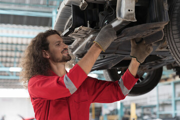 Car mechanic and auto service shop concept. Male car mechanic repair automobile axle, suspension and disc brake in auto repair shop. Technician checking steel brake disk, wheel hub in garage workshop