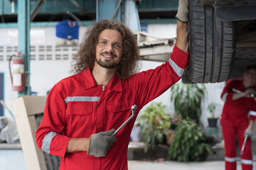 Car mechanic and auto service shop concept. Male car mechanic repair automobile axle, suspension and disc brake in auto repair shop. Technician checking steel brake disk, wheel hub in garage workshop