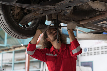 Car mechanic and auto service shop concept. Male car mechanic repair automobile axle, suspension and disc brake in auto repair shop. Technician checking steel brake disk, wheel hub in garage workshop