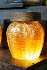 Transparent glass jar with honey and honeycombs.