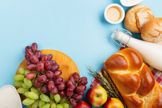 Jewish Shavuot Holiday Card. Dairy Products, Apples, Cheese, Grapes, Bread, Milk on Blue Background.