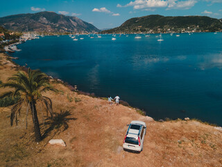 overhead view of the couple standing near car looking at sea harbor with yachts and boats