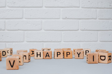 Eco-friendly cubes. The word happy is made up of wooden cubes on a gray concrete background. Front view