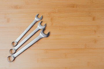 A set of working tools, different size wrenches on a brown wooden, bamboo background. Top view