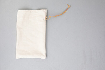 Beige fabric bag for storage on a gray background. Eco bags for multiple use, conscious consumption. Flat lay